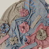 Textile piece with striped fabric and floral embellishments on a neutral background