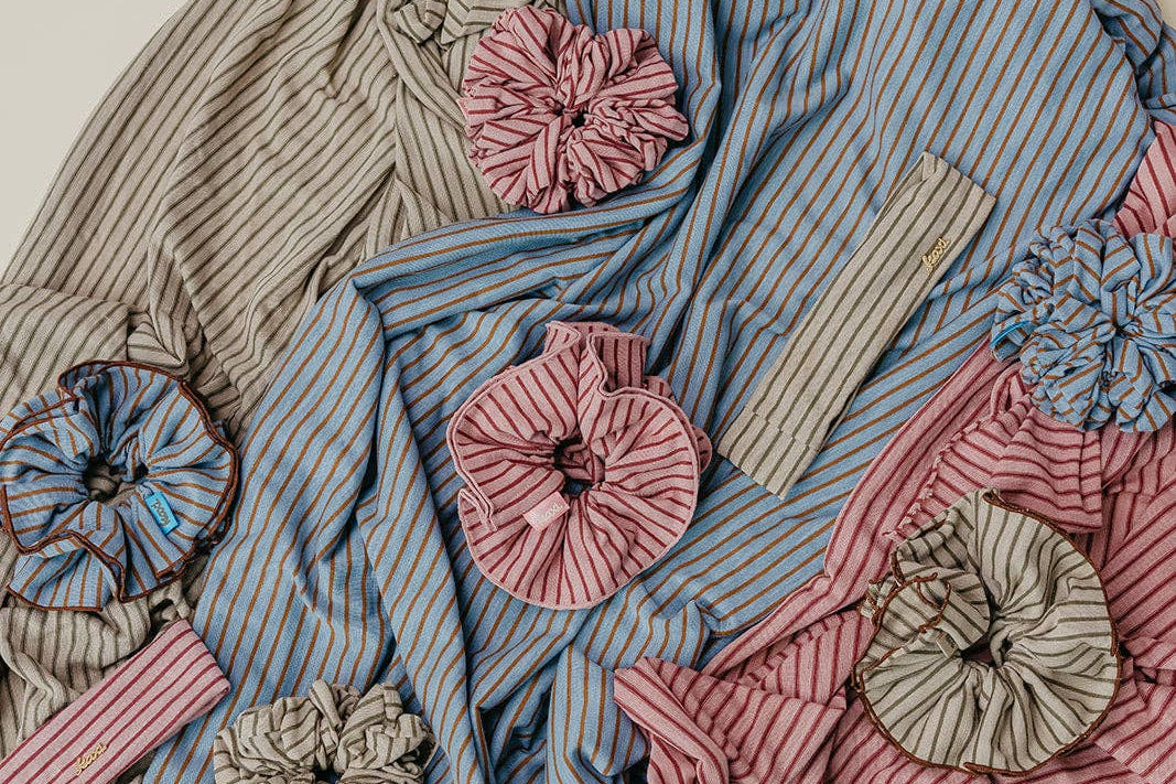 Textile piece with striped fabric and floral embellishments on a neutral background