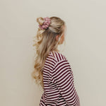 Woman with styled hair and a striped dress against a beige background