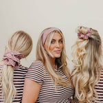 Three women in matching striped shirts with hairstyles using pink scrunchies.