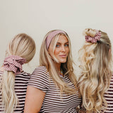 Three women in matching striped shirts with hairstyles using pink scrunchies.