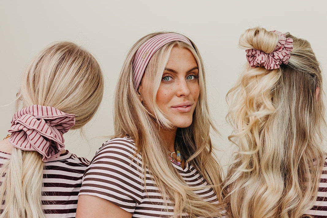 Three women in matching striped shirts with hairstyles using pink scrunchies.