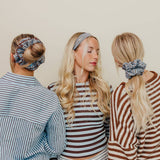 Three women wearing striped shirts and scrunchies with a neutral background