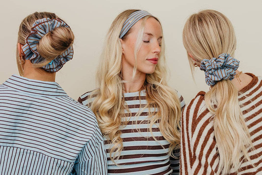 Three women wearing striped shirts and scrunchies with a neutral background