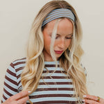 Woman wearing a striped shirt and headband against a plain background