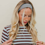 Woman wearing a striped shirt and headband against a plain background