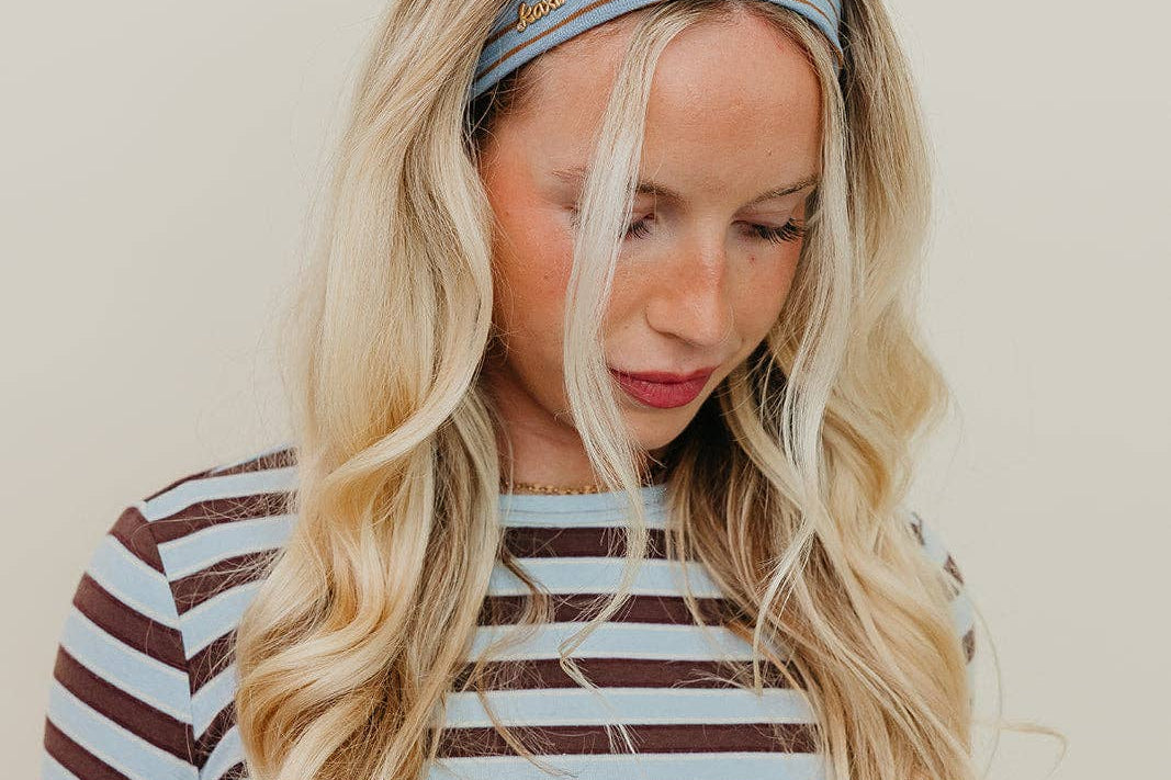 Woman wearing a striped shirt and headband against a plain background