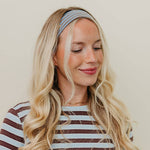 Woman wearing a striped shirt and headband against a plain background