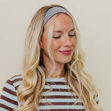 Woman wearing a striped shirt and headband against a plain background