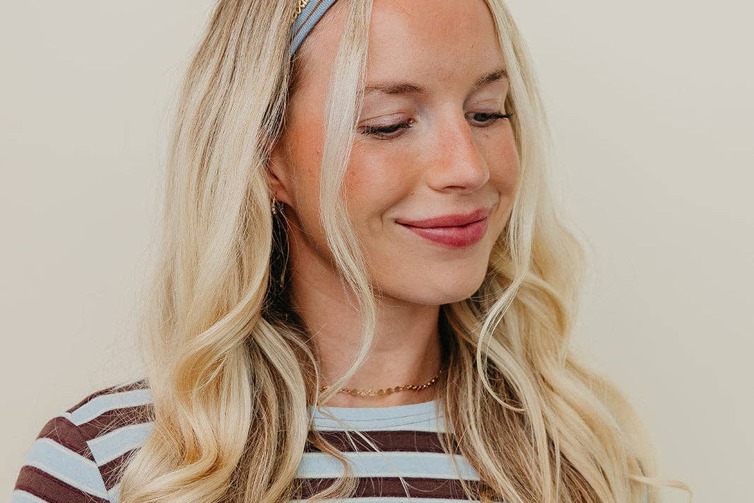 Woman wearing a striped shirt and headband against a plain background