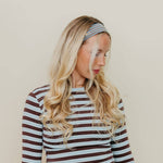 Woman wearing a striped long-sleeve top and headband against a beige background