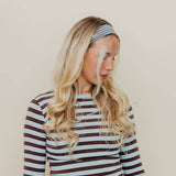Woman wearing a striped long-sleeve top and headband against a beige background