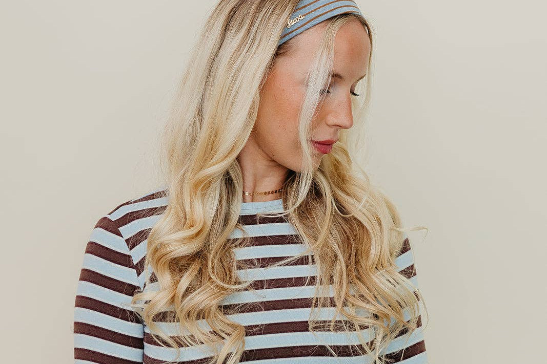 Woman wearing a striped long-sleeve top and headband against a beige background