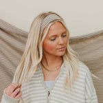 Woman wearing a striped sweater and headband with a neutral background
