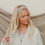 Woman wearing a striped sweater and headband with a neutral background