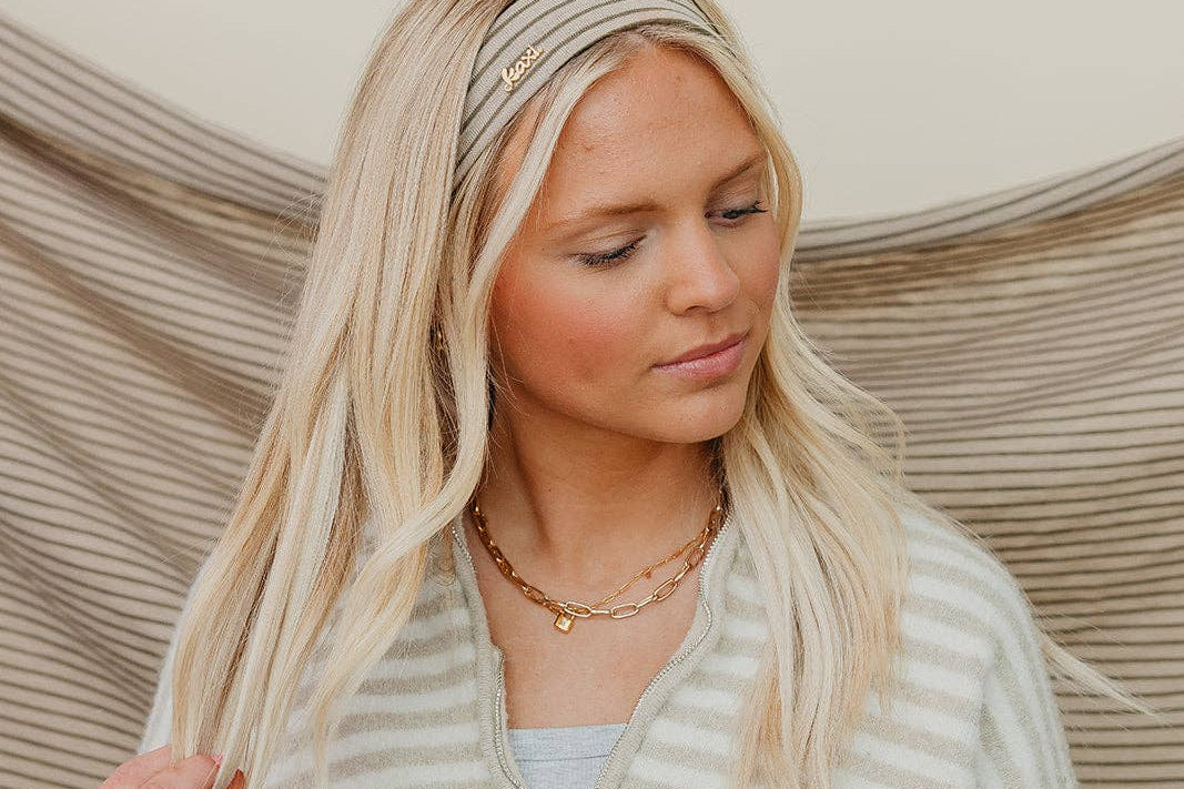 Woman wearing a striped sweater and headband with a neutral background