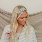 Woman with blonde hair wearing a headband against a neutral background