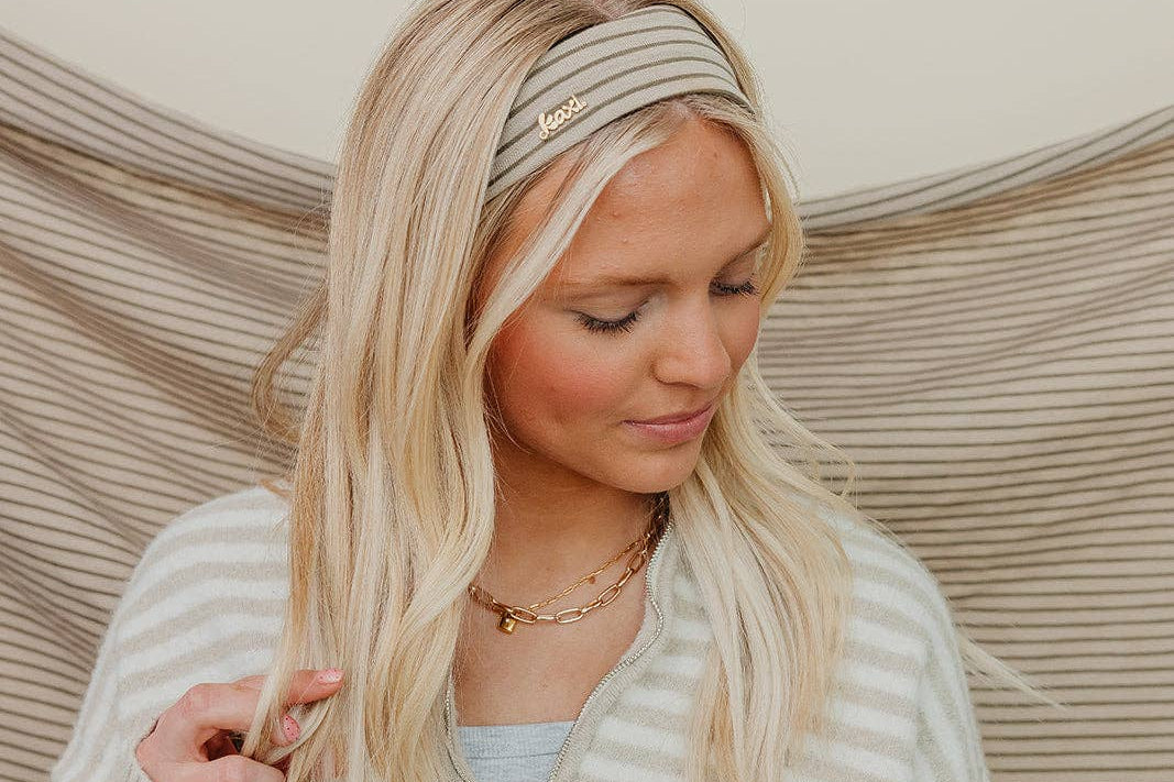 Woman with blonde hair wearing a headband against a neutral background