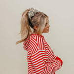 Woman wearing a red and white striped sweater against a plain background