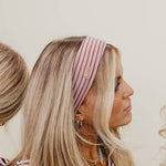 Woman wearing a striped headband and striped shirt against a neutral background