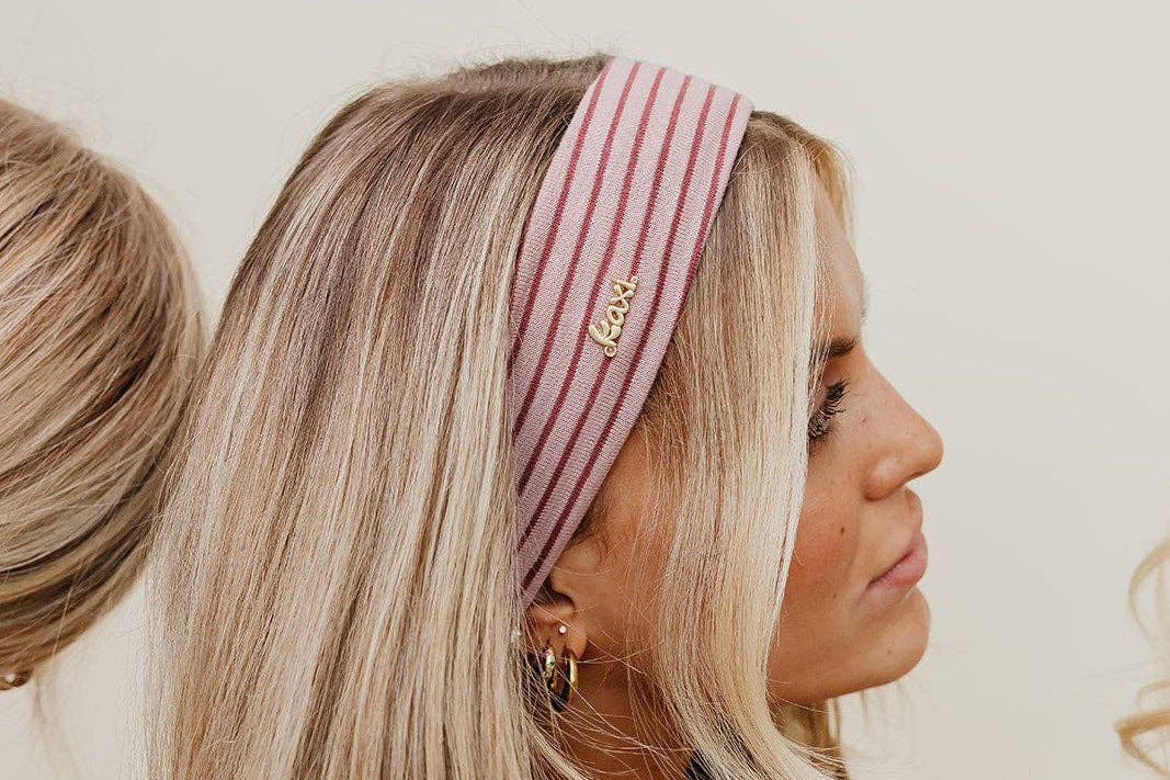 Woman wearing a striped headband and striped shirt against a neutral background