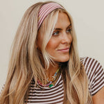 Woman wearing a striped shirt and pink headband against a plain background