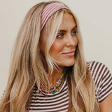 Woman wearing a striped shirt and pink headband against a plain background