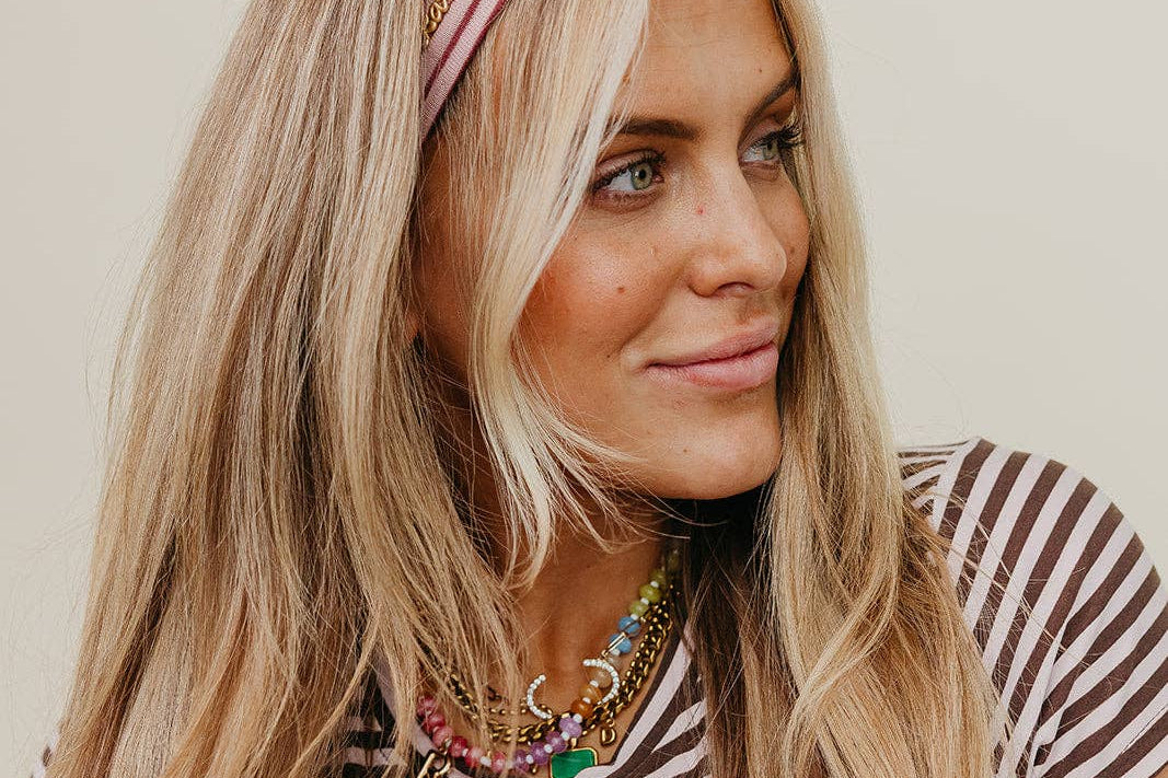 Woman wearing a striped shirt and pink headband against a plain background