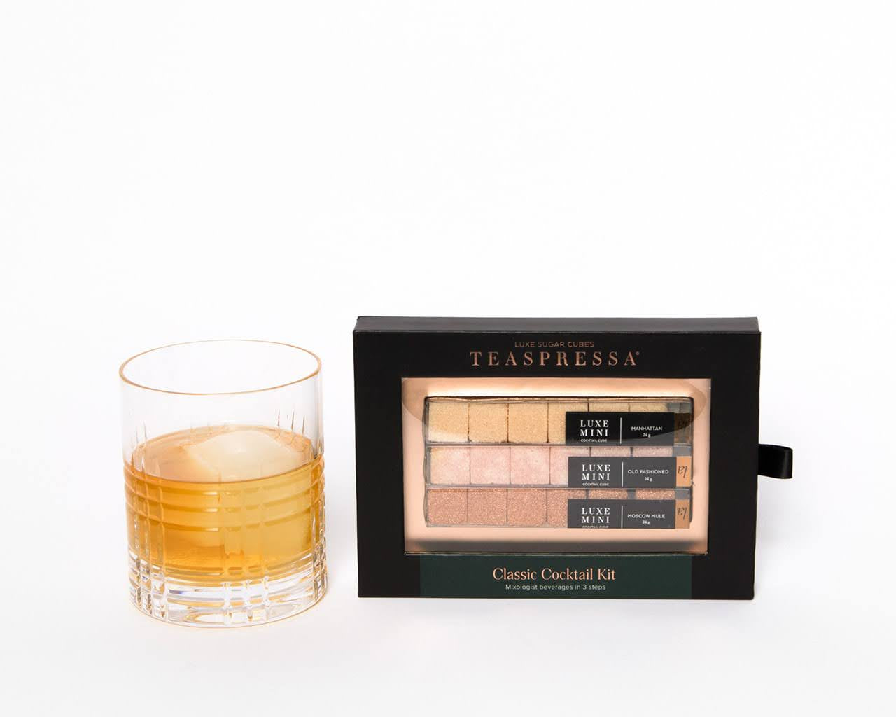 Luxury Classic Cocktail Kit by Teaspressa showing cubes in sophisticated black packaging sitting next to cocktail with ice cube ball. White background.