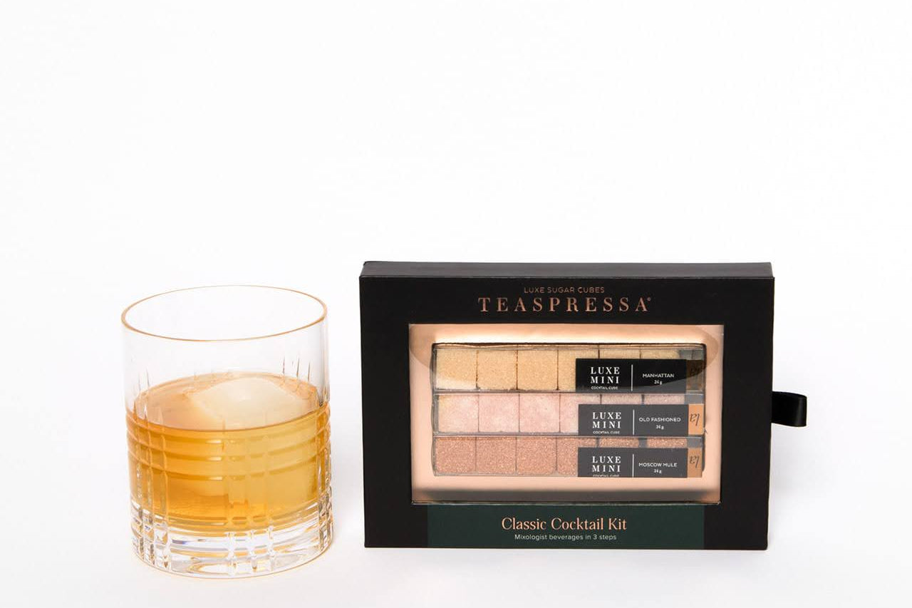 Luxury Classic Cocktail Kit by Teaspressa showing cubes in sophisticated black packaging sitting next to cocktail with ice cube ball. White background.
