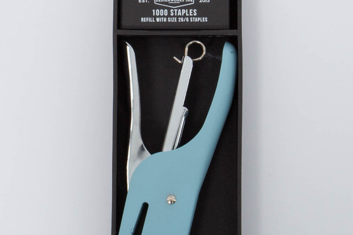 Light blue and silver Standard Issue Stapler by Designworks in black packaging bog with 1000 staples. 