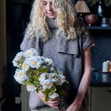 Abigail Ahern Artificial Dahlia Evening Dew, a woman in a grey sweater holding an armful of the cream faux dahlias