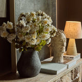 Abigail Ahern Artificial Dahlia Evening Dew stems arranged in a dark vase on a console with a lamp and books