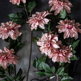 Abigail Ahern Artificial Dahlia Flamingo, several pink dahlia stems with dark green leaves laid on a dark surface