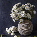 Abigail Ahern Artificial Rose Cream Spray, full bouquet of white faux roses in a textured stone vase on a dark background