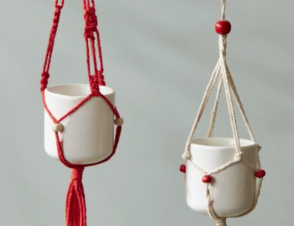 Macrame Tillandsia Holder Ornament, miniature macrame plant hanger in red and in cream with a tassel, hanging on an evergreen branch