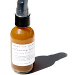 Among the Flowers Balancing Honey Cleanser, close-up of the amber pump bottle casting a shadow