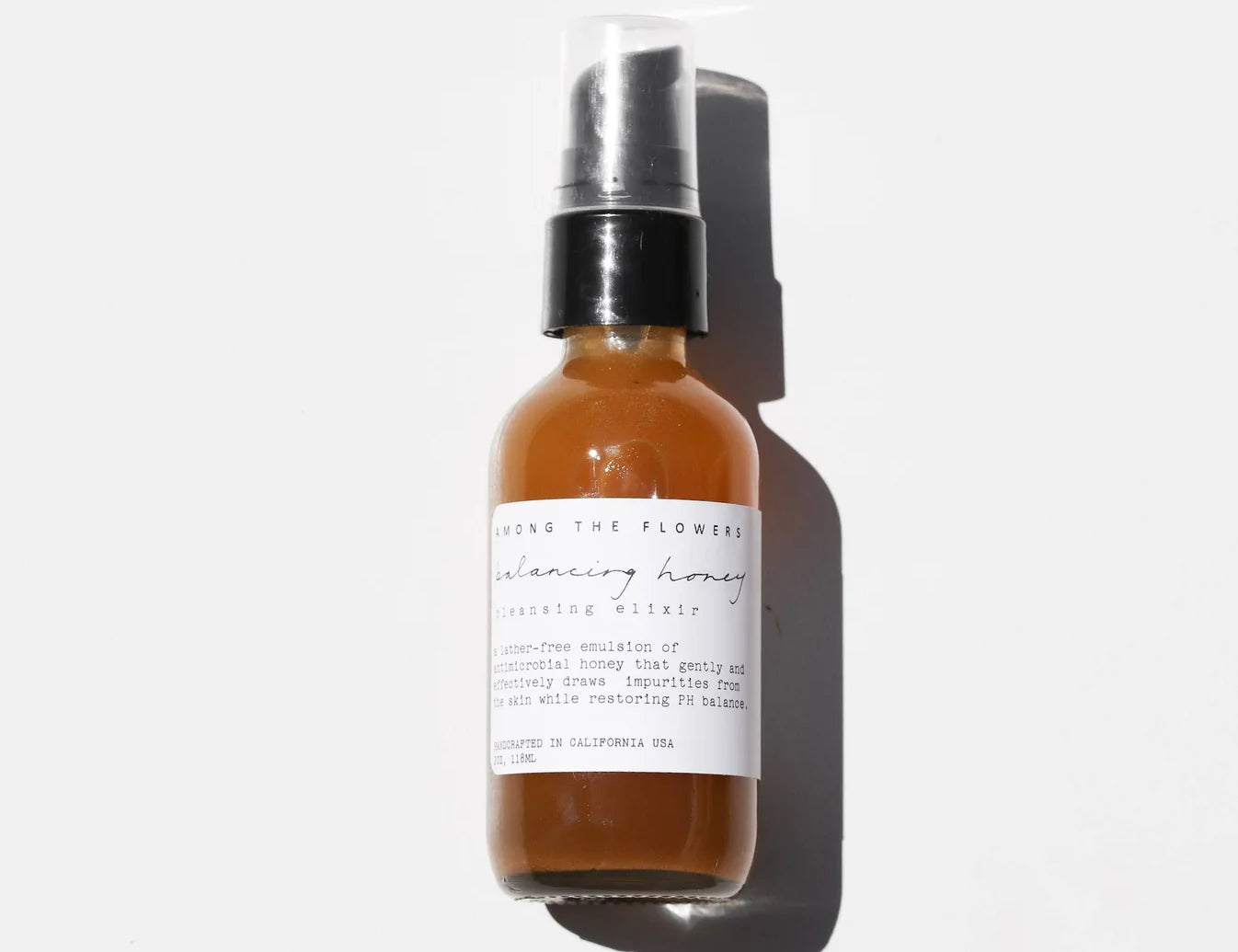 Among the Flowers Balancing Honey Cleanser, amber glass pump bottle with a white label on white