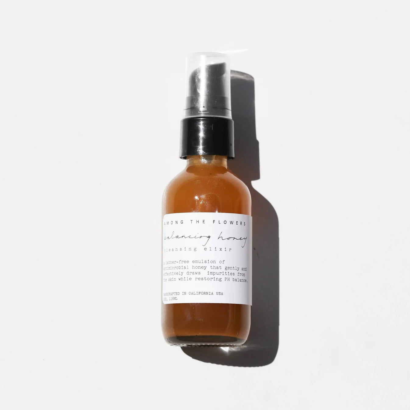 Among the Flowers Balancing Honey Cleanser, amber glass pump bottle with a white label on white