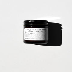 Among the Flowers Calm Mom Breast Salve in a small amber glass jar with a black lid