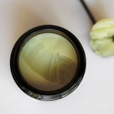 Among the Flowers Calm Mom Breast Salve open jar from above showing the pale yellow salve