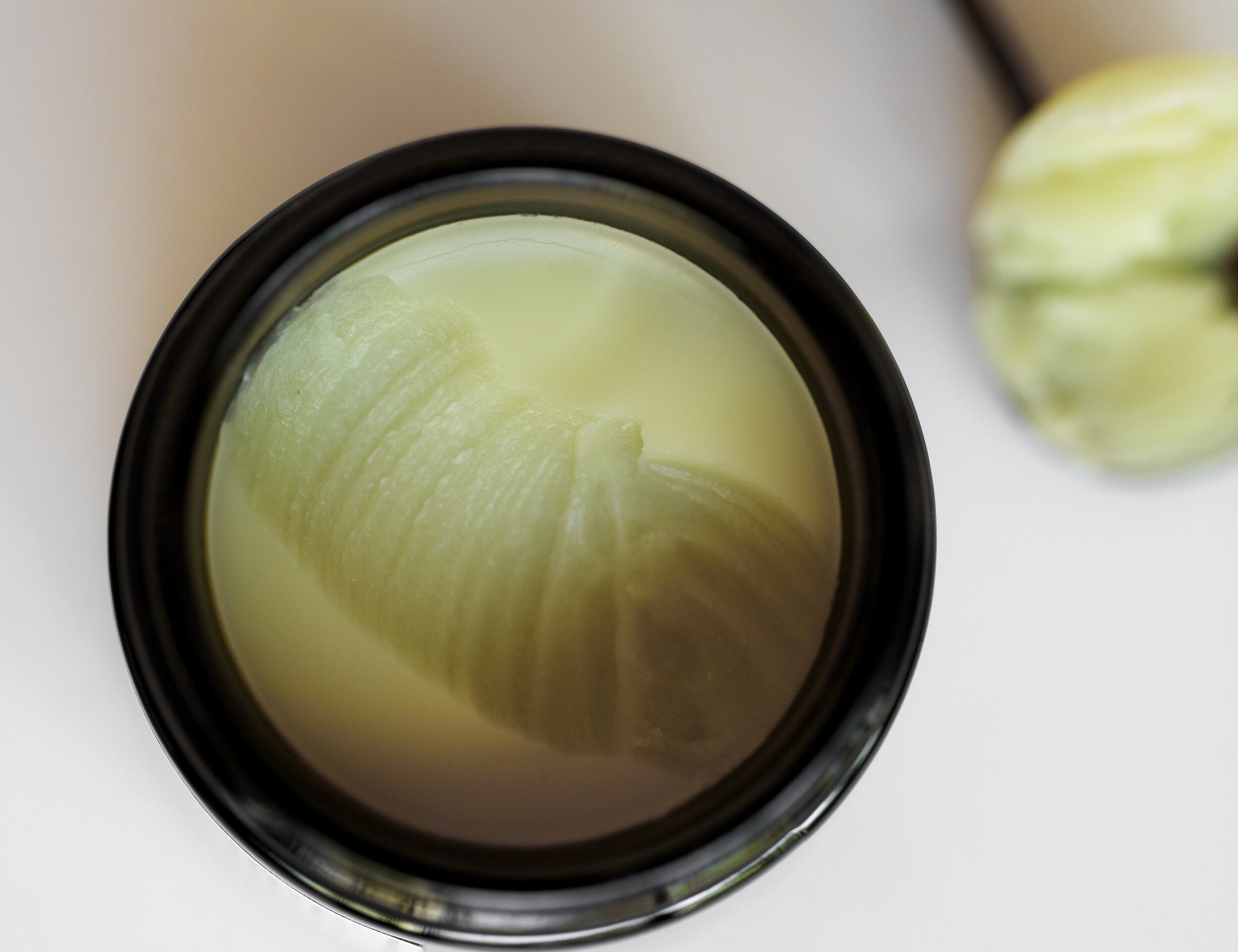 Among the Flowers Calm Mom Breast Salve open jar from above showing the pale yellow salve
