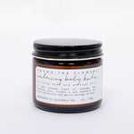 Among the Flowers Calming Baby Balm in an amber glass jar with a black lid and white label