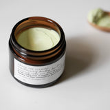 Among the Flowers Calming Baby Balm open jar from above with a wooden spoon beside it