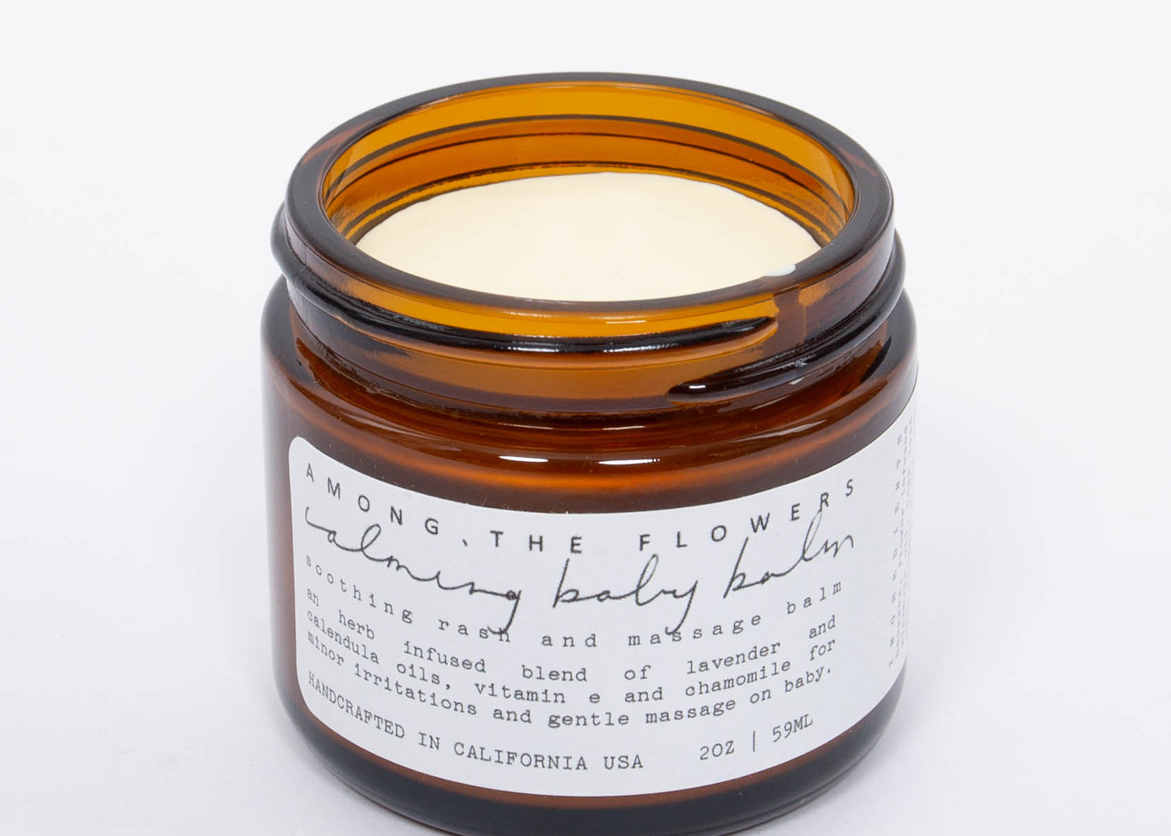 Among the Flowers Calming Baby Balm open amber jar showing the pale yellow balm