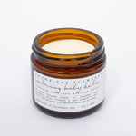 Among the Flowers Calming Baby Balm open amber jar showing the pale yellow balm
