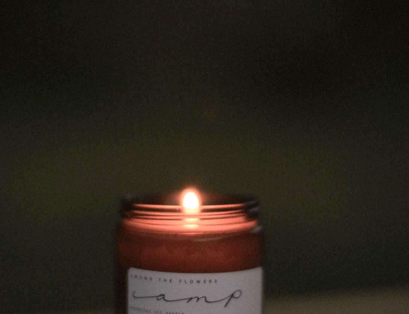 Among the Flowers Camp Candle lit and glowing in a dark room