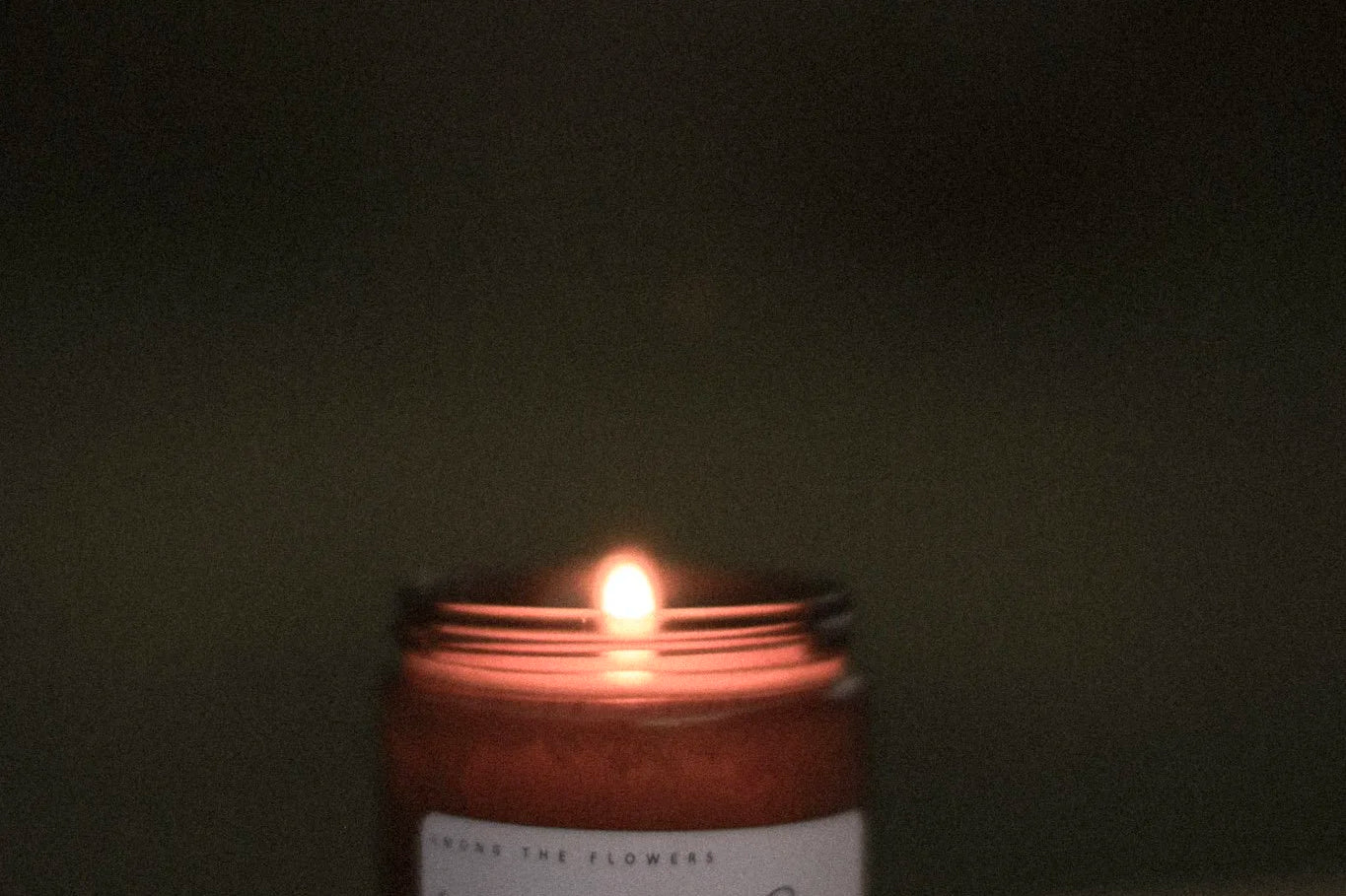 Among the Flowers Camp Candle lit and glowing in a dark room