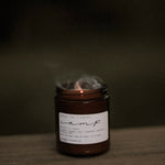Among the Flowers Camp Candle with smoke rising from the wick after being blown out