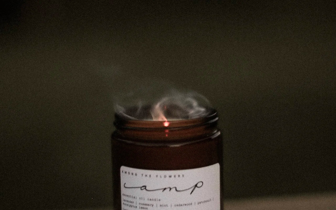 Among the Flowers Camp Candle with smoke rising from the wick after being blown out